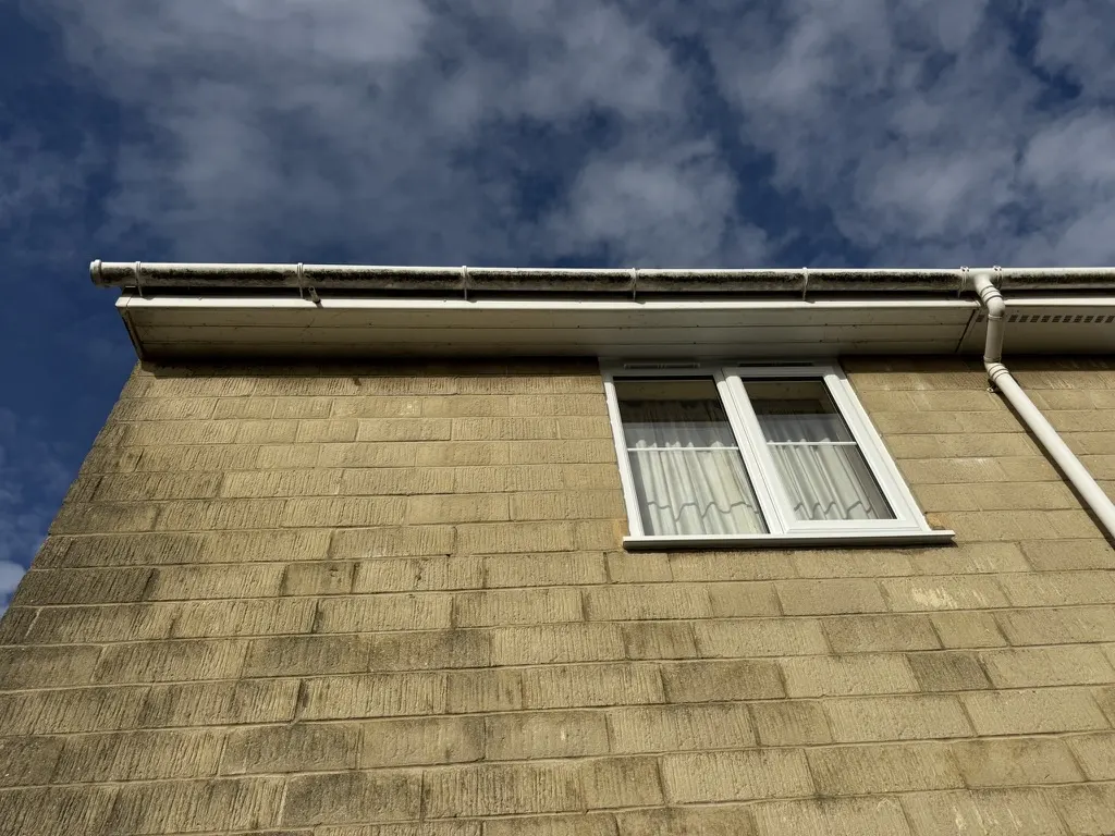 A gutter and fascia before cleaning, grey and streaked