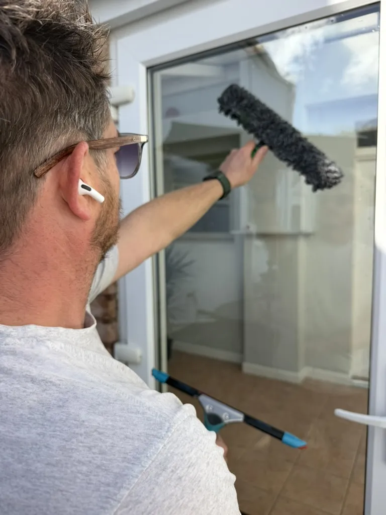 Jason, owner of PureClean, cleaning a glass door with a window brush