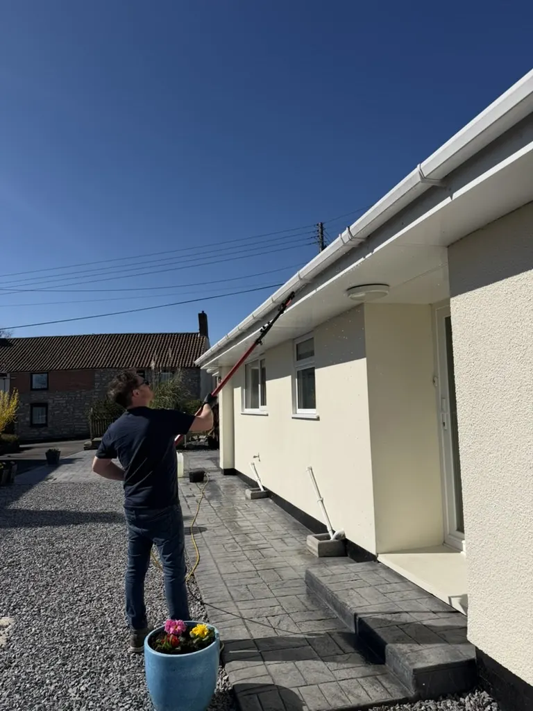 Jason cleaning a bungalow’s fascia and windows with a water-fed pole